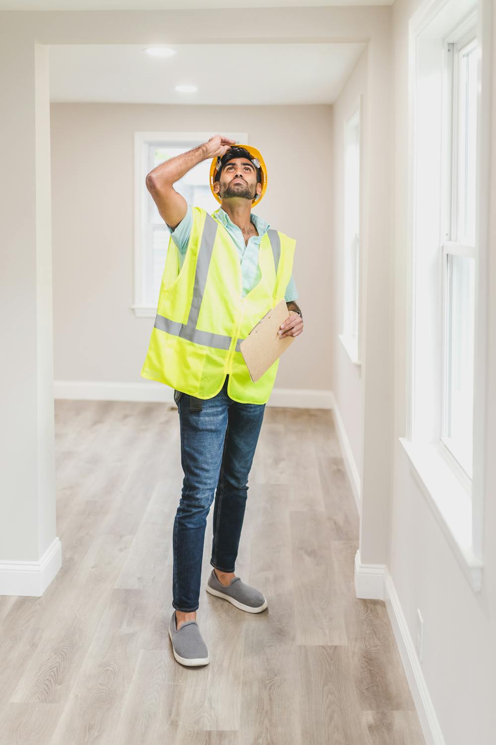 A contractor in a hi-vis vest and hard hat checking a room during an on-site estimate.